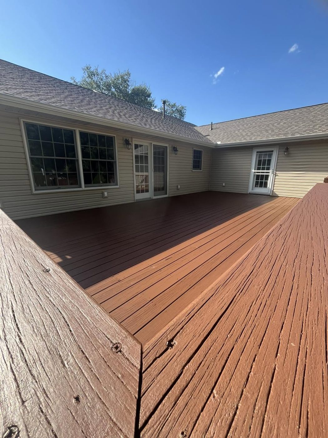 Restored deck stained in a rich redwood tone beside the house