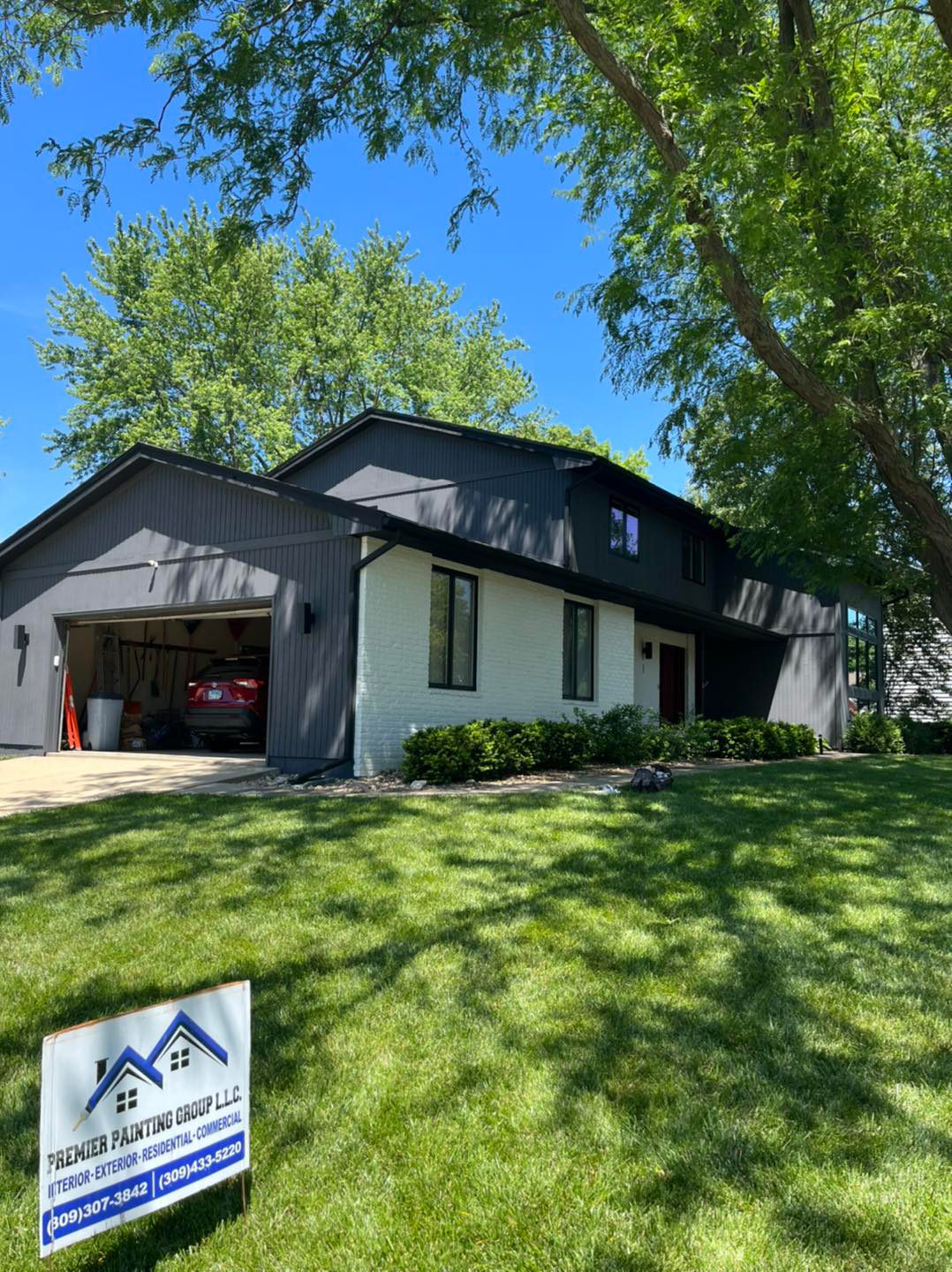 A freshly painted charcoal and white home with a Premier Painting Group yard sign on the lawn